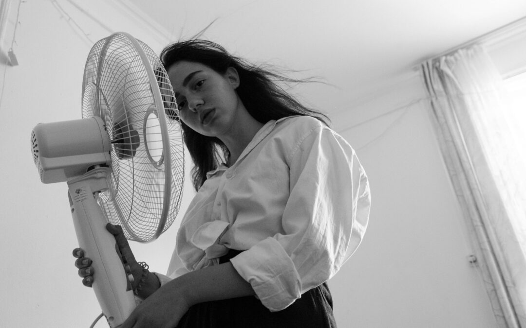 woman in white dress shirt standing beside white pedestal fan